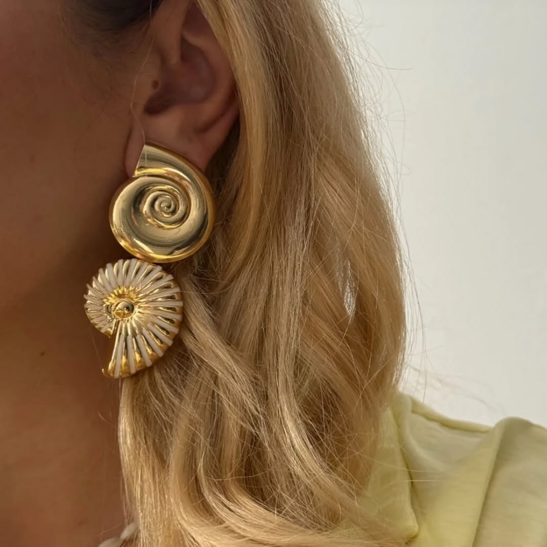 Modèle portant de magnifiques boucles d'oreilles coquillages dorées signées Turquoise